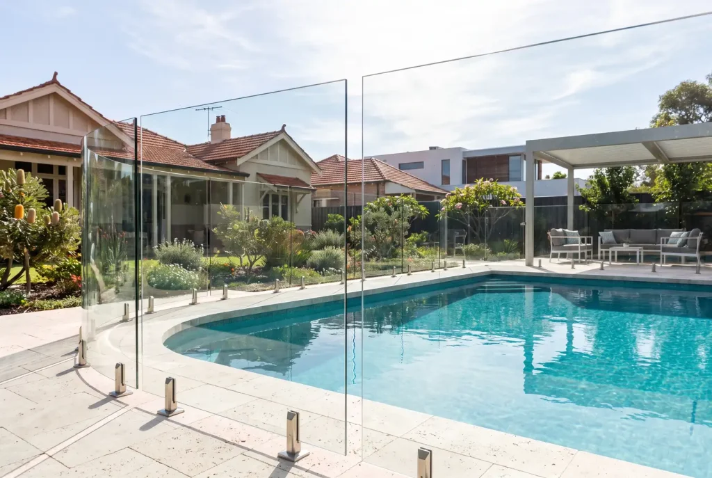 Frameless glass pool fence with steel spigots around a backyard pool in Northbridge, Perth