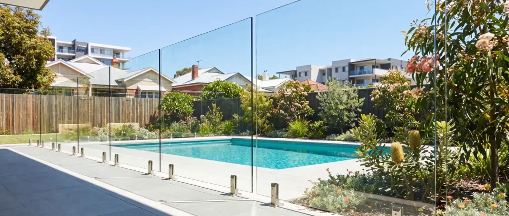 Low-angle frameless glass pool fencing framing a turquoise backyard pool in Northbridge, WA