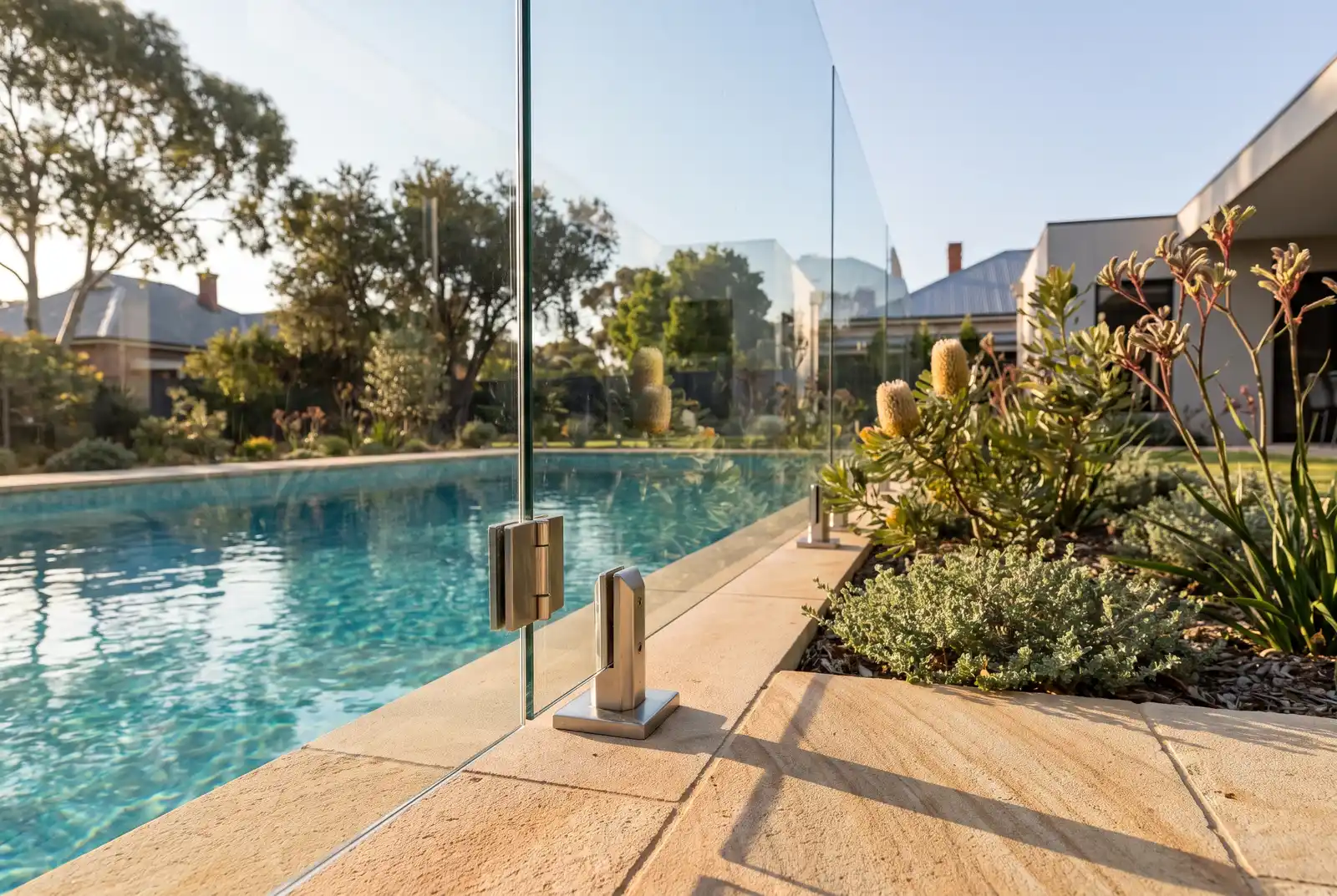 Frameless glass pool fencing detail with stainless steel spigots beside a backyard pool in Northbridge WA